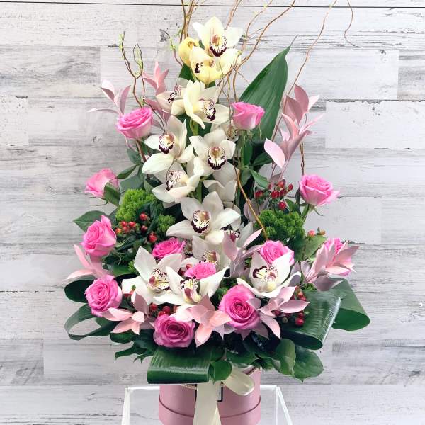 Pink roses and white orchids in a tall pink box arrangement