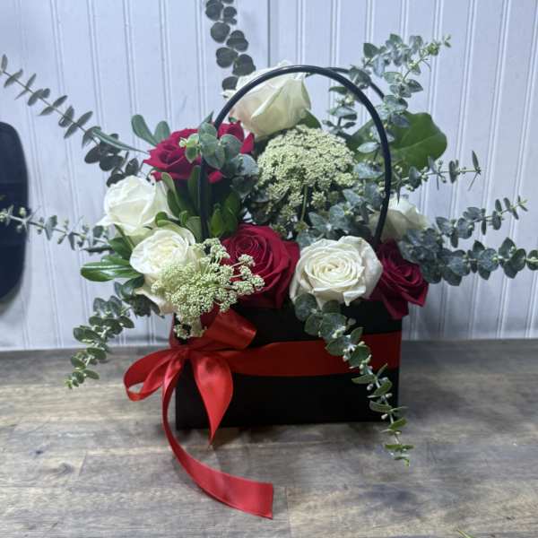 Black basket arrangement of red and white roses with a red ribbon