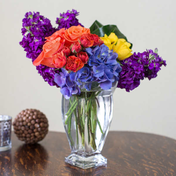 Colorful bouquet of roses and hydrangeas in a clear glass vase