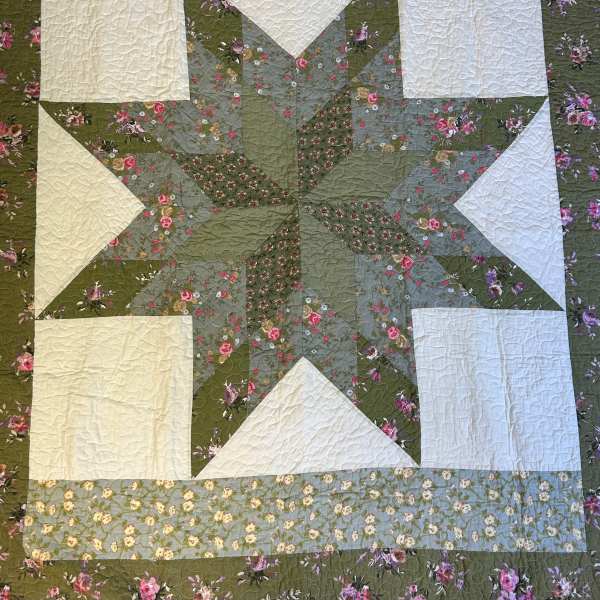 Patchwork quilt with a large green and cream star and floral patterned fabrics