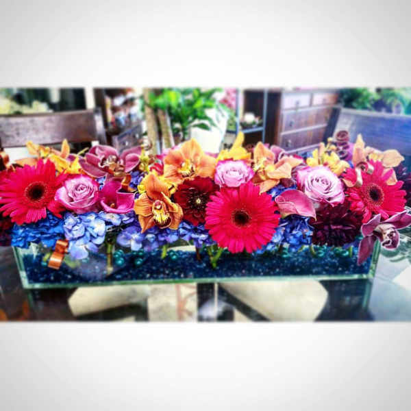 Bright mixed flower arrangement in a rectangular glass vase