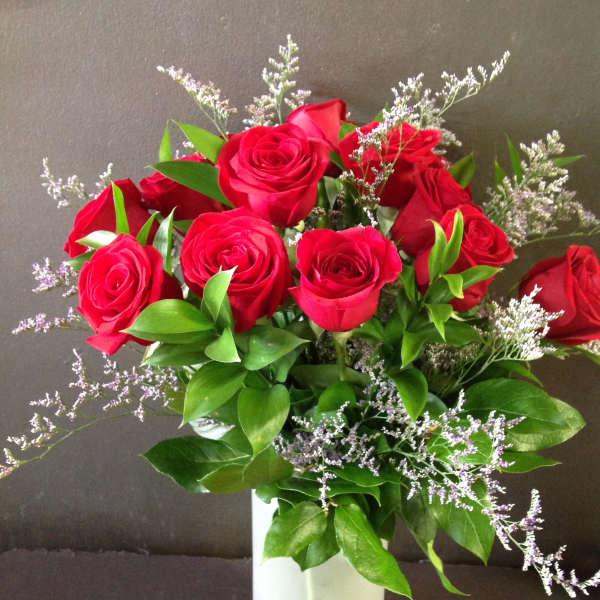 Red roses in a white vase with purple filler flowers