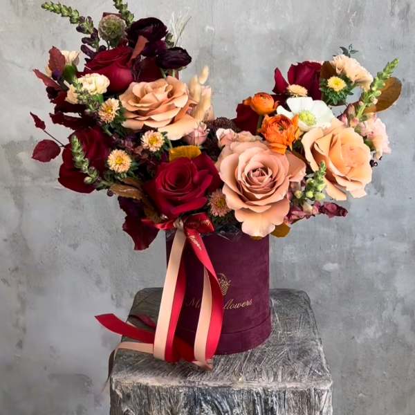 Bouquet of red and blush roses in a burgundy hat box with ribbon