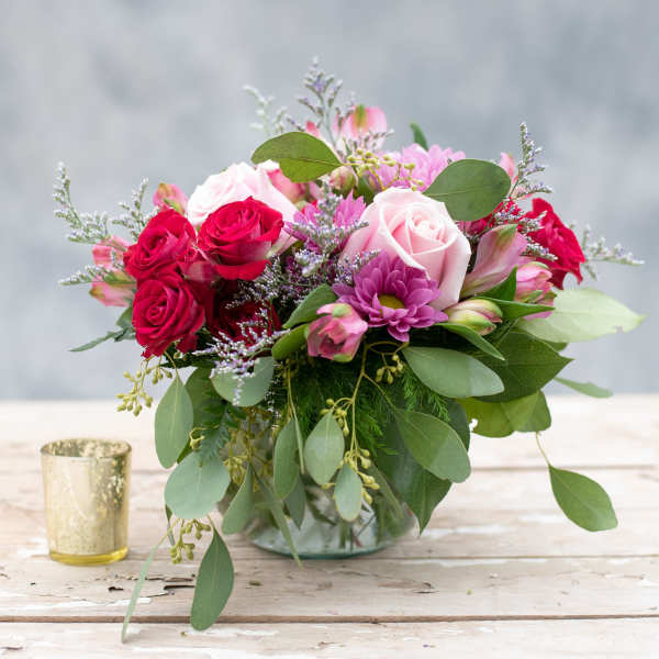 Pink and red roses with purple blooms in a glass vase