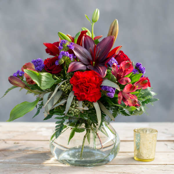 Mixed bouquet of red and purple flowers in a clear glass vase