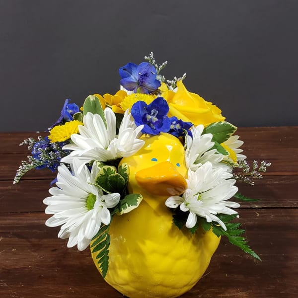 Yellow duck-shaped vase with white daisies and blue flowers