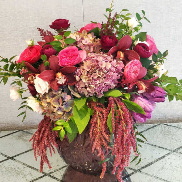 Large bouquet of pink and burgundy flowers in a dark vase