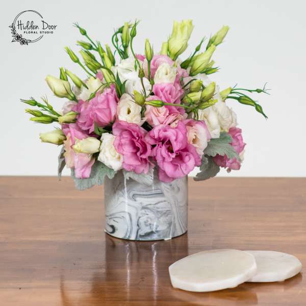 Pink and white flowers arranged in a marbled vase on a table