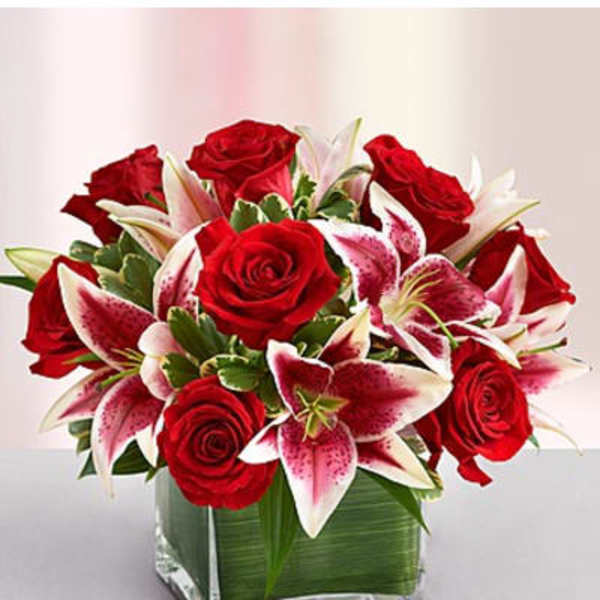 Red roses and pink lilies arranged in a square glass vase
