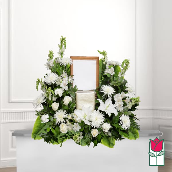 White floral funeral arrangement with a framed center and candle