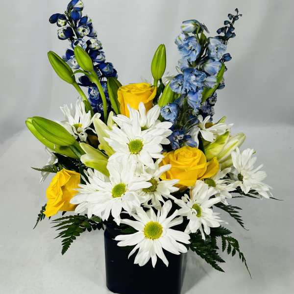 Yellow roses and white daisies in a black vase with blue flowers