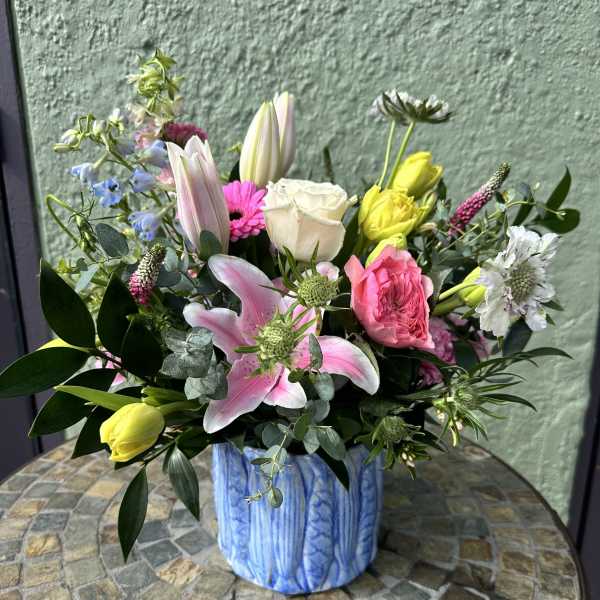 Colorful mix of lilies, roses, tulips and other blooms in a blue ceramic vase