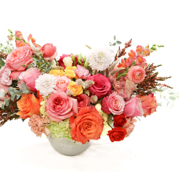 Mixed pink and orange flower arrangement in a round vase