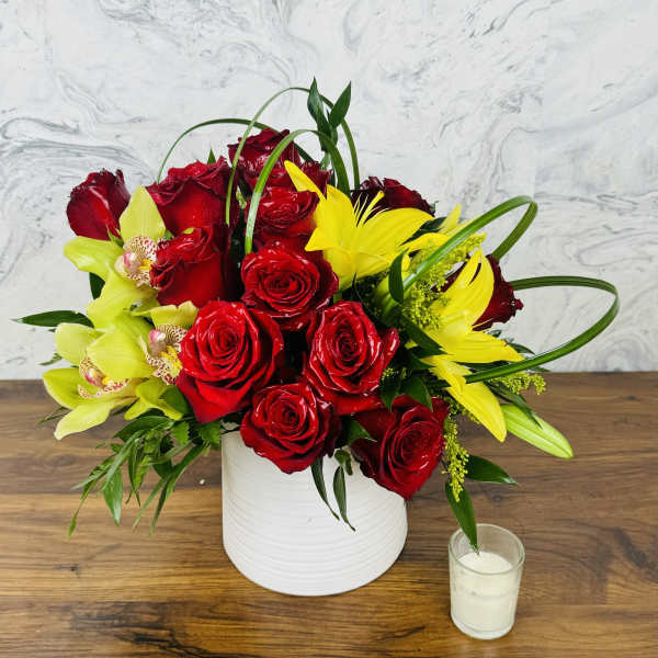 Red roses and yellow lilies arranged in a white vase
