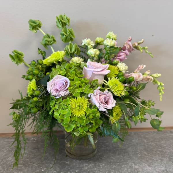 Mixed bouquet of lavender roses, green chrysanthemums, and hydrangea in a glass vase