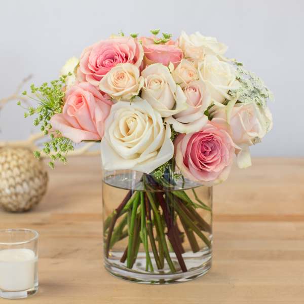 Pink and white roses arranged in a clear glass vase