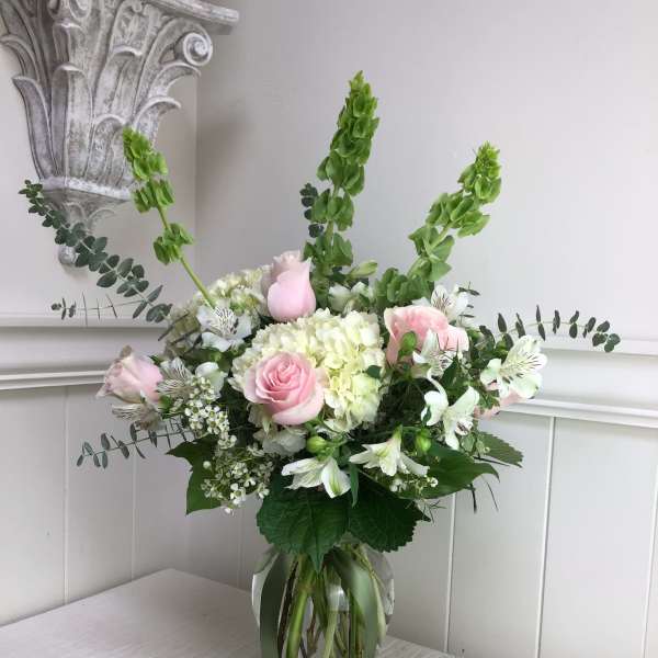 Pink roses and white flowers arranged in a glass vase