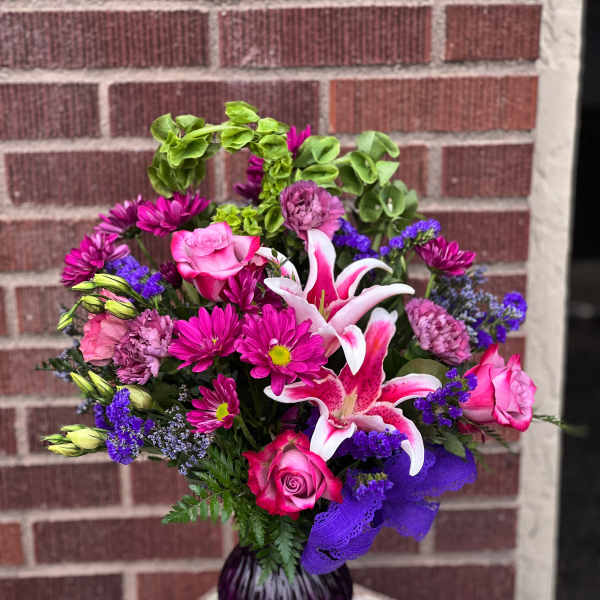 Pink and purple bouquet with lilies and roses in a purple vase