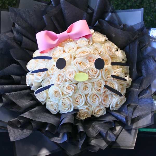 Bouquet of cream roses styled like a Hello Kitty face with a pink bow