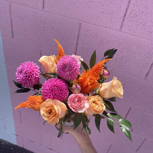 Handheld bouquet of pink and peach flowers with orange accents