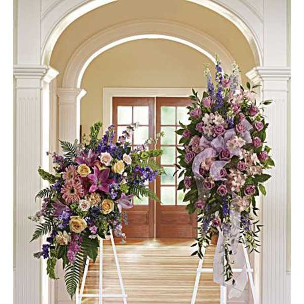 Two large floral standing sprays on white easels in a hallway