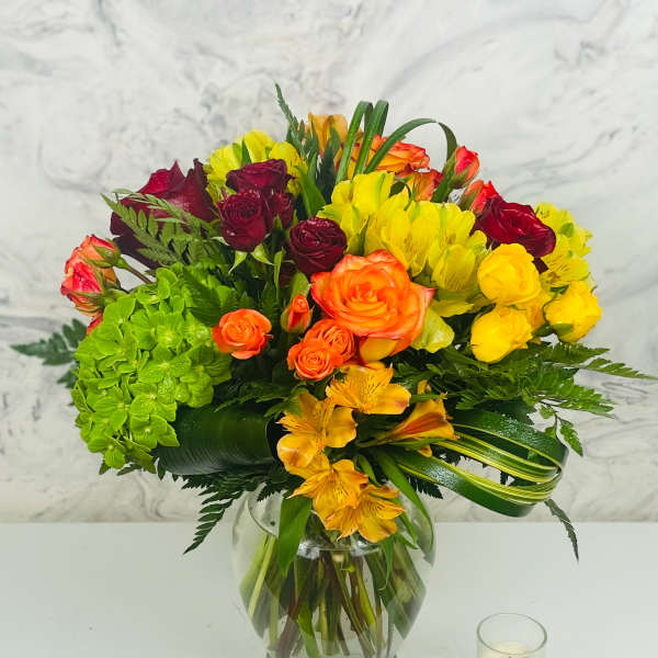 Mixed bouquet of roses, hydrangea, and alstroemeria in a glass vase