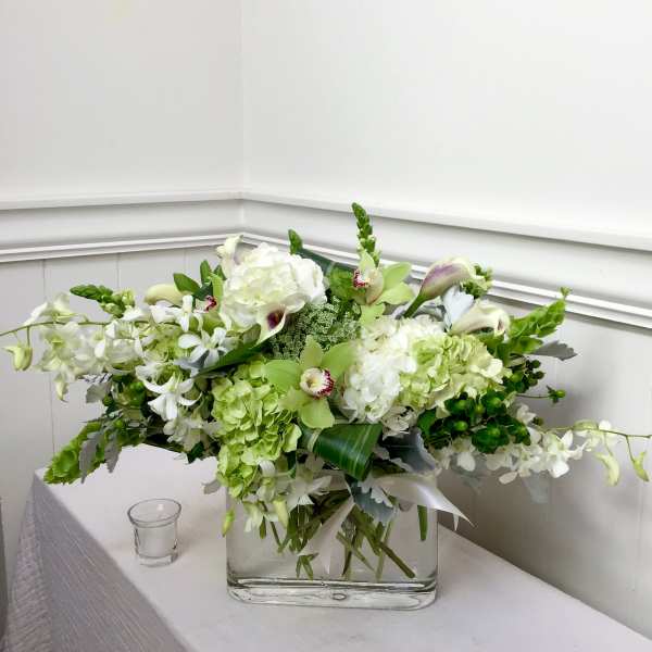 White and green floral arrangement in a clear rectangular vase