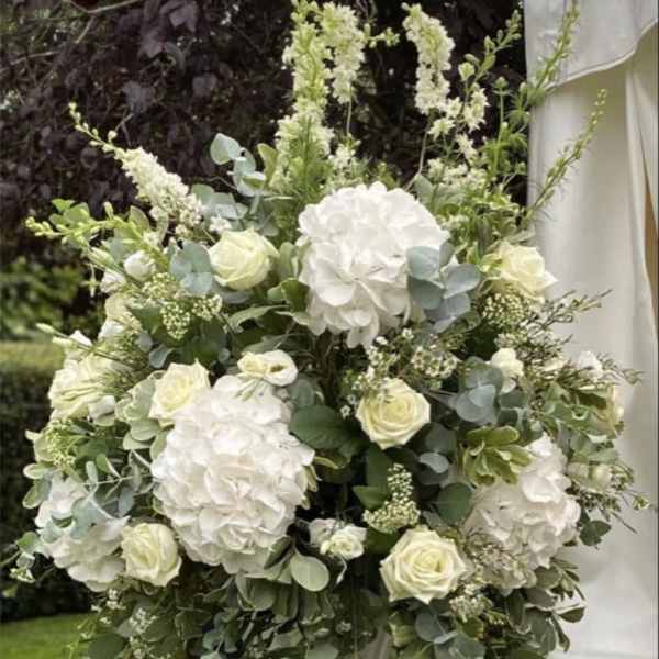 White floral arrangement in a tall white pedestal vase