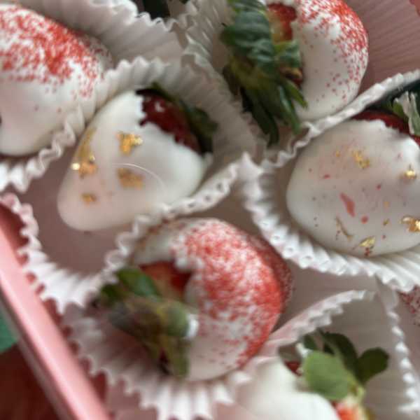 Box of chocolate-covered strawberries with white and red drizzle