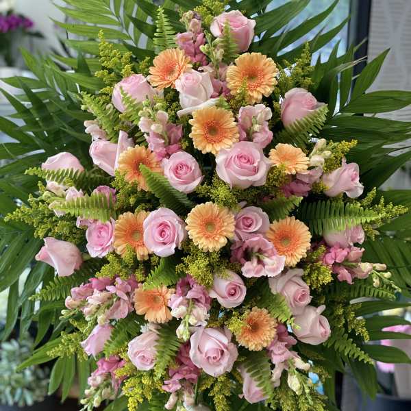 Pink roses and peach gerbera daisies in a large standing arrangement