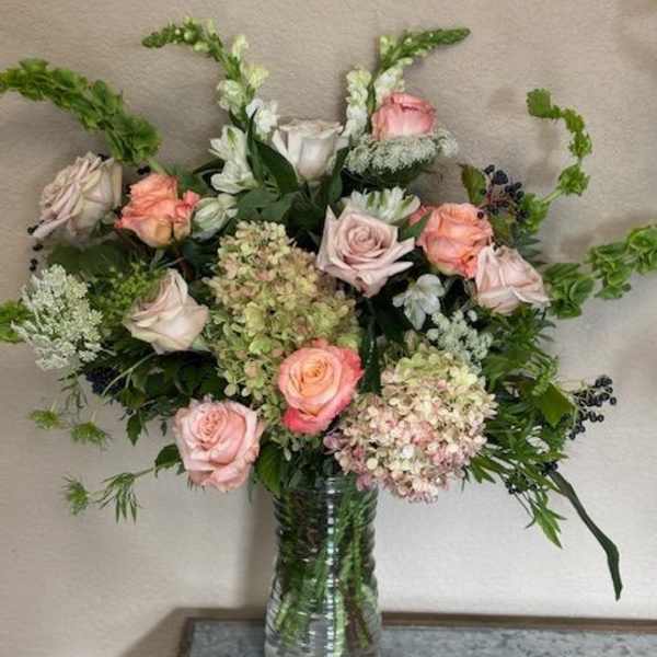 Pink and white roses with hydrangeas in a clear glass vase