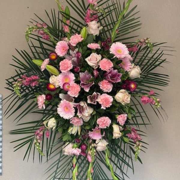 Large pink and white funeral spray with palm fronds