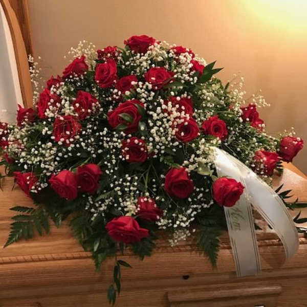 Red rose casket spray with white baby's breath on a wooden casket
