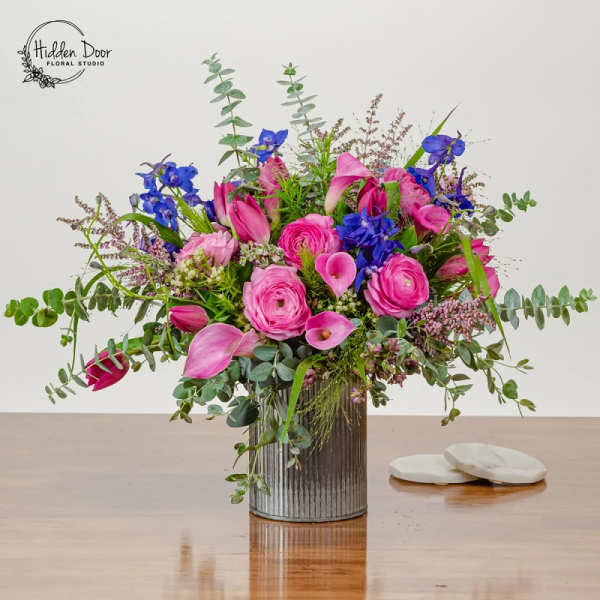 Pink and blue mixed flower arrangement in a ribbed metal vase