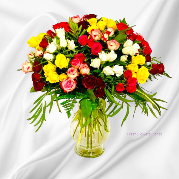 Mixed roses in red, white, pink, and yellow in a glass vase