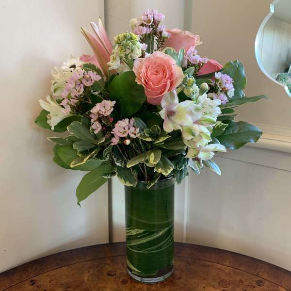 Pink and white mixed bouquet in a tall green glass vase