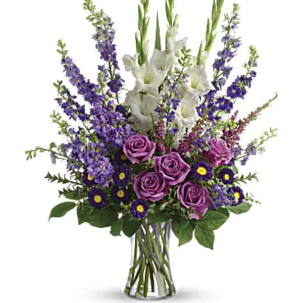 Purple roses and white gladiolus in a clear glass vase
