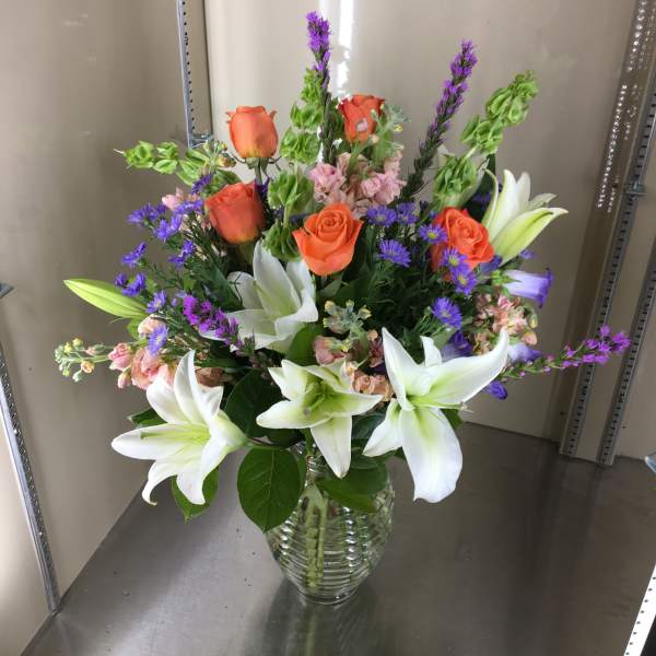 Bouquet of orange roses and white lilies in a glass vase