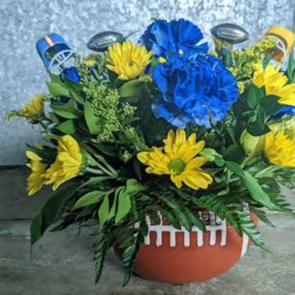 Blue and yellow floral arrangement in a football-shaped container