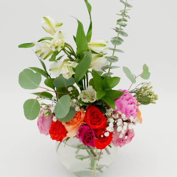 Mixed bouquet of roses and white lilies in a clear glass vase
