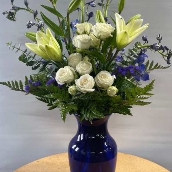 White roses and pale lilies in a blue vase