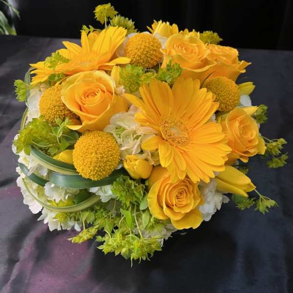 Yellow roses and gerbera daisies in a low bouquet with white flowers