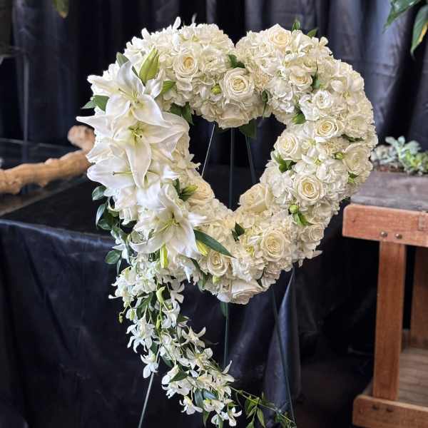 White floral heart-shaped funeral wreath with cascading orchids