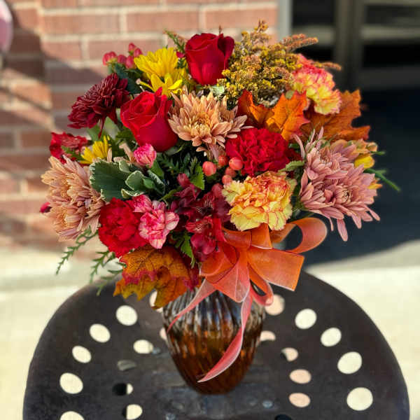 Autumn bouquet of red roses, chrysanthemums, and carnations in a glass vase