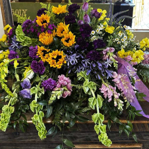 Large casket spray with yellow, purple, and pink flowers