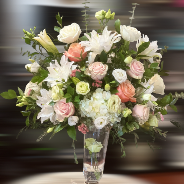 Tall bouquet of white and blush flowers in a clear glass vase