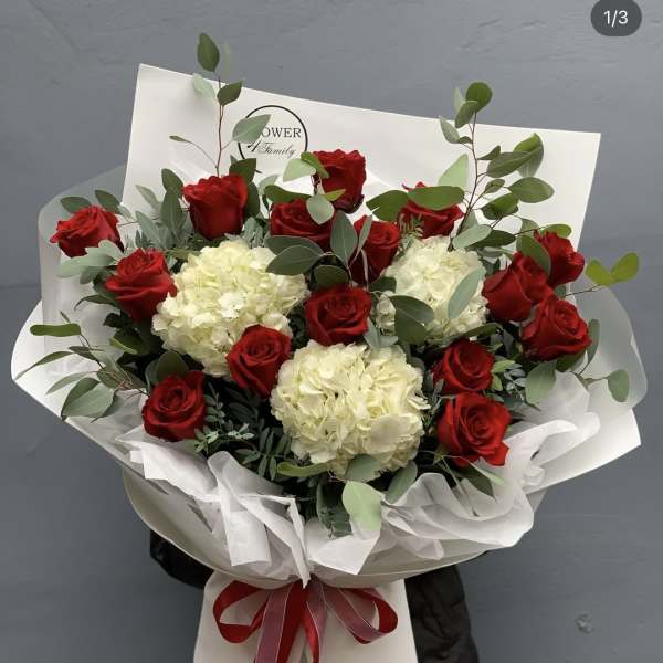 Bouquet of red roses and white hydrangeas wrapped in white paper