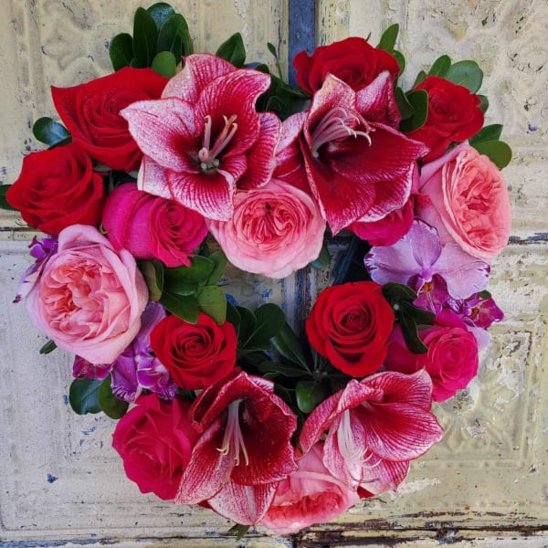 Heart-shaped bouquet of red and pink roses with amaryllis blooms