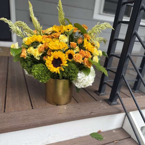 Yellow and orange flowers arranged in a gold vase