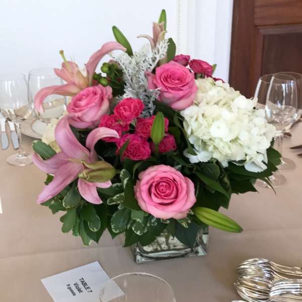 Pink roses and lilies arranged with white hydrangeas in a square glass vase